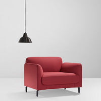 Red upholstered armchair with a smooth finish, paired with a sleek black pendant lamp. Modern minimalistic design.