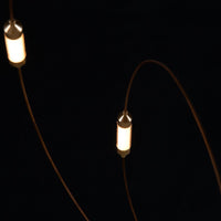 Modern light fixture featuring warm white lights and sleek brown cords on a black background. Elegant and minimal design.