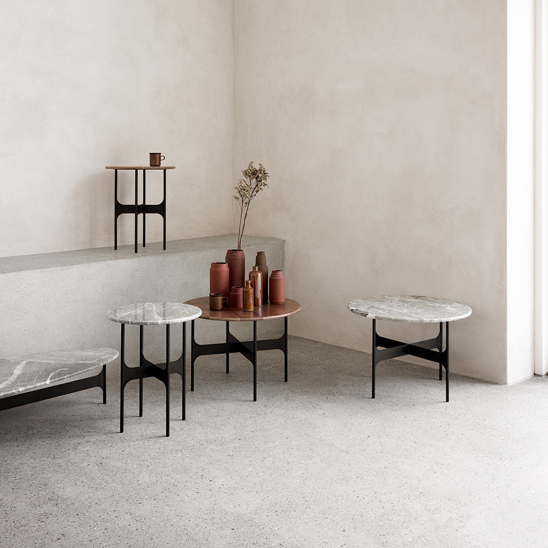 Modern tables with marble and wood tops in neutral tones, set against a minimalist beige background.