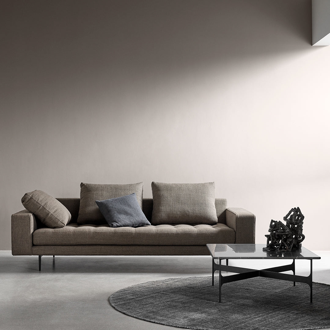 Stylish gray couch with textured cushions, paired with a sleek black and white coffee table on a circular gray rug.