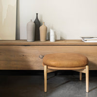 "Elegant beige and tan stool on a wooden surface with soft, neutral vases against a light background."