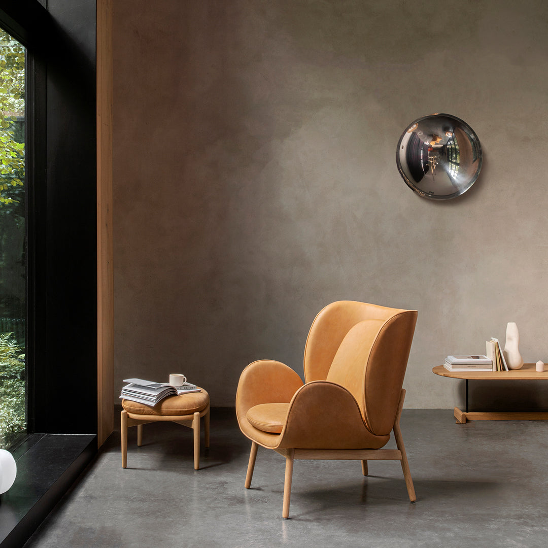 "Vintage-inspired orange armchair with smooth fabric and wooden legs, set against a neutral gray wall backdrop."
