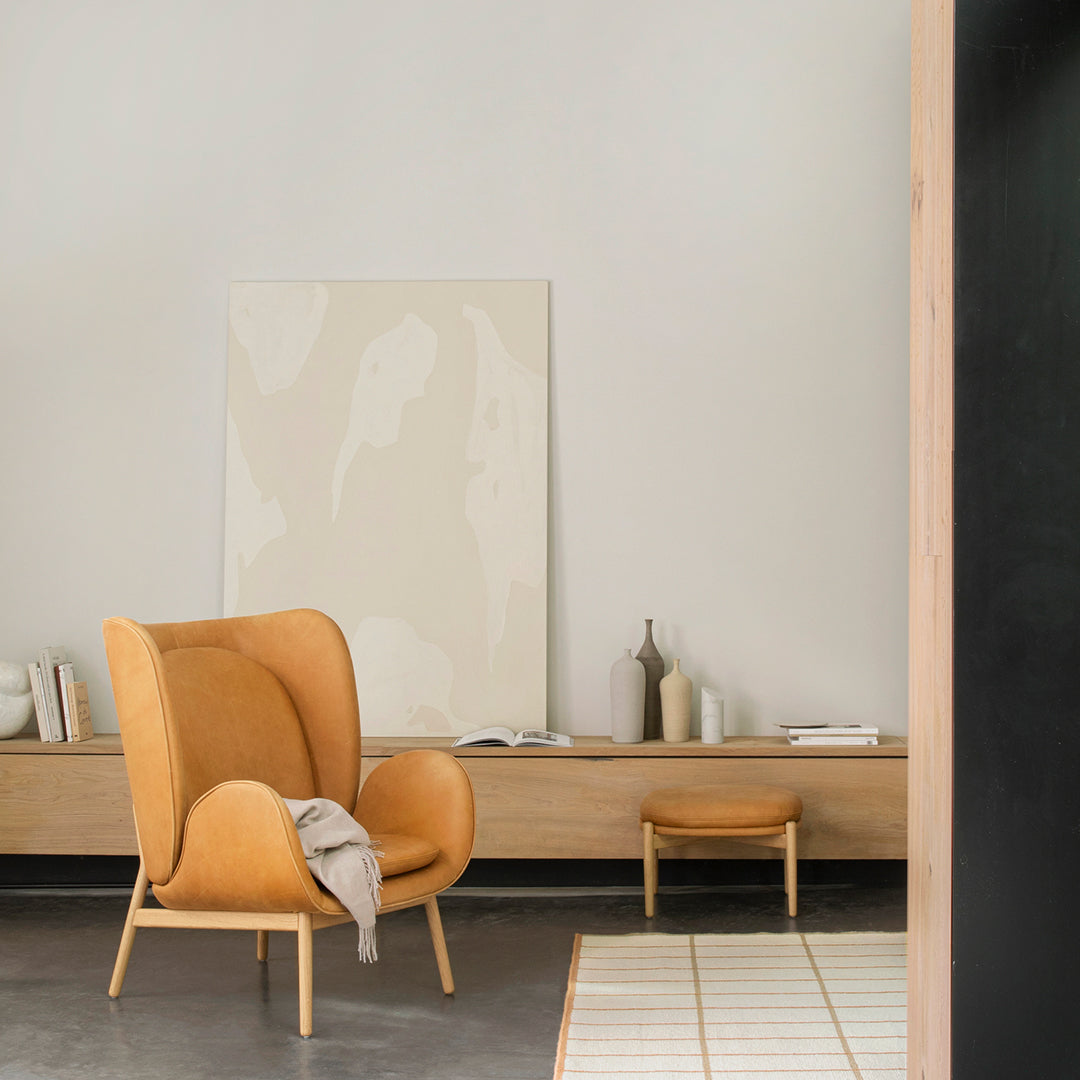 Orange armchair with a textured pattern, gray floor, neutral walls, and abstract light beige artwork in a modern setting.
