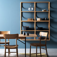 Light wood furniture with a navy blue wall background, showcasing a mix of neutral and dark ceramic dishes on shelves.