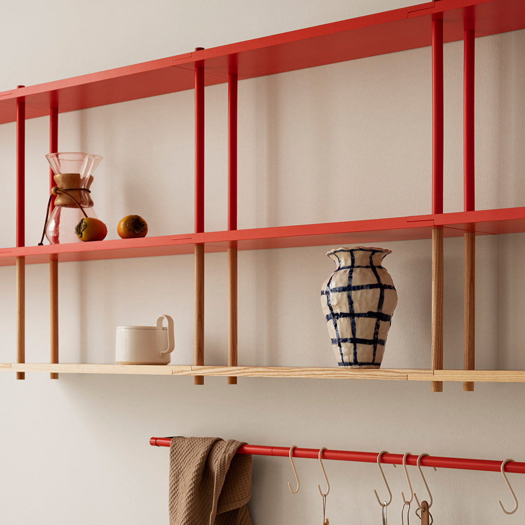 Red shelves with wooden accents display a blue-and-white patterned vase, enhancing modern decor aesthetics.