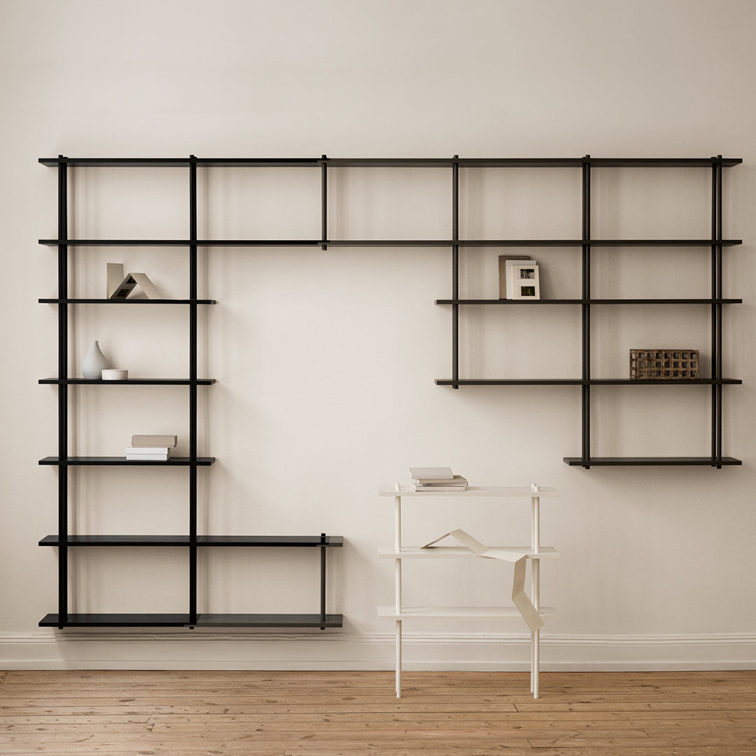 Modern black open shelving unit against a neutral wall, featuring geometric patterns and minimalist design elements.
