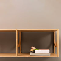 Natural wood shelf with a light maple finish against a neutral beige wall, featuring soft floral and stacked book decor.