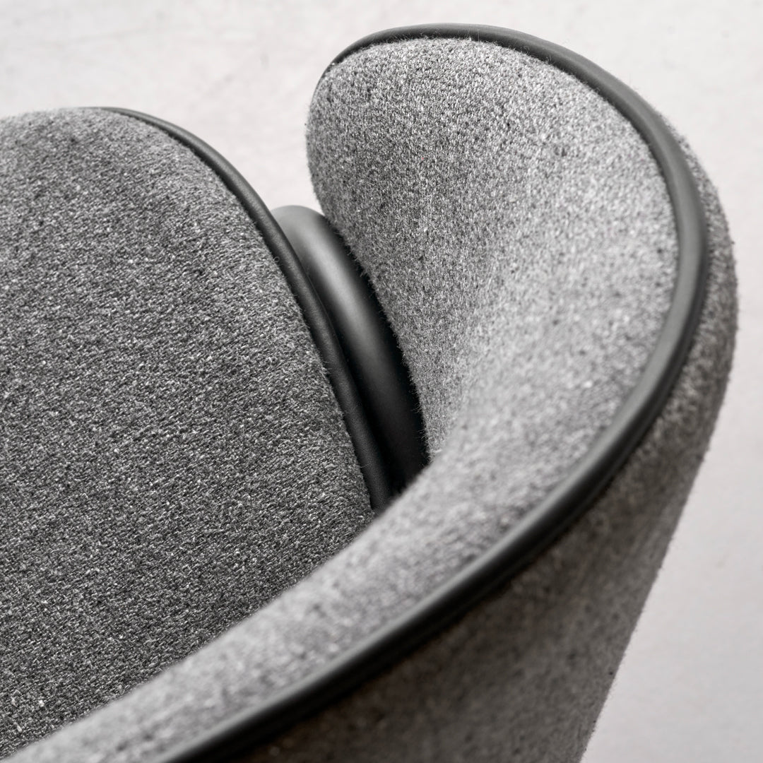 Gray upholstered chair with smooth, curved lines and a contrasting black trim. Subtle textured pattern adds depth.