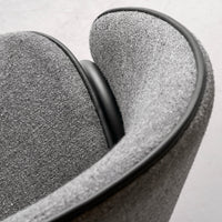 Gray upholstered chair with smooth, curved lines and a contrasting black trim. Subtle textured pattern adds depth.