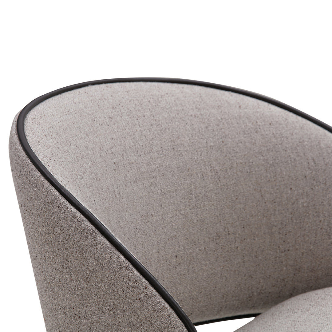 Gray fabric chair with a smooth texture and contrasting black piping trim. Stylish and modern design element.
