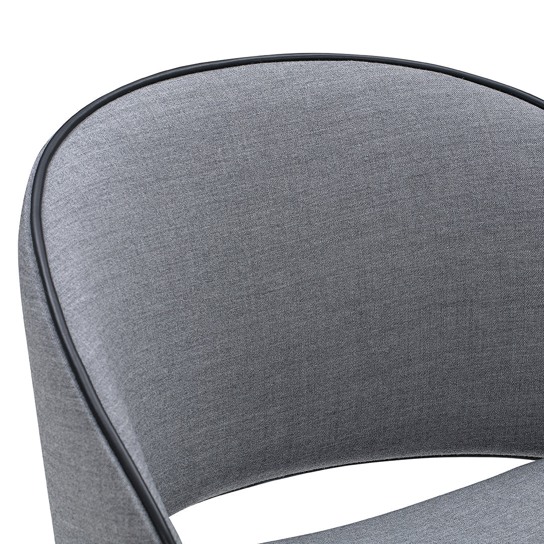 Gray upholstered chair with a smooth texture and black piping detail, featuring a modern, curved design.