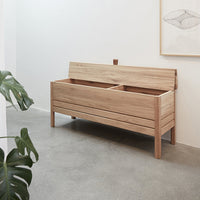 Light wood storage bench with a smooth finish and minimalist design, featuring natural grain patterns and a neutral palette.