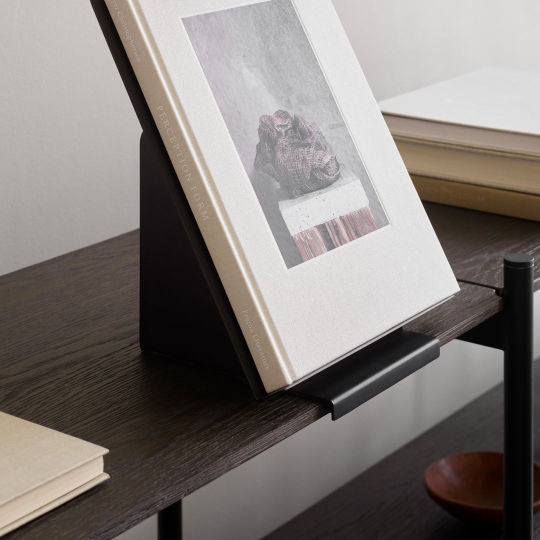 "Elegant book stand with a minimalist black base, displaying a neutral-toned book with subtle texture and patterned cover."