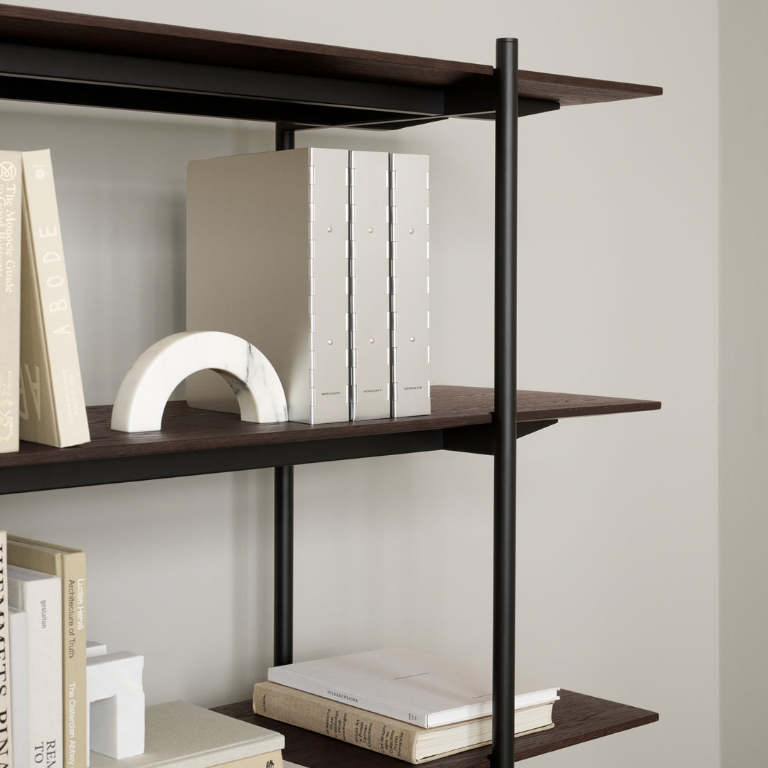 Dark brown shelves with white books and a light curved decor piece, featuring a minimalist and modern design.