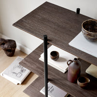 Dark wood shelves with black accents, showcasing earthy ceramic vases and minimalist white notepads. Modern decor.