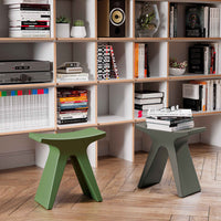 Green and gray contemporary stools with a sleek, geometric design, set against a modern bookshelf backdrop.