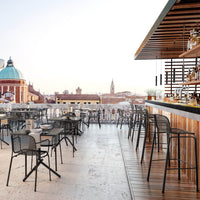 Stylish black outdoor bar stools with a natural wood countertop and modern urban skyline backdrop.