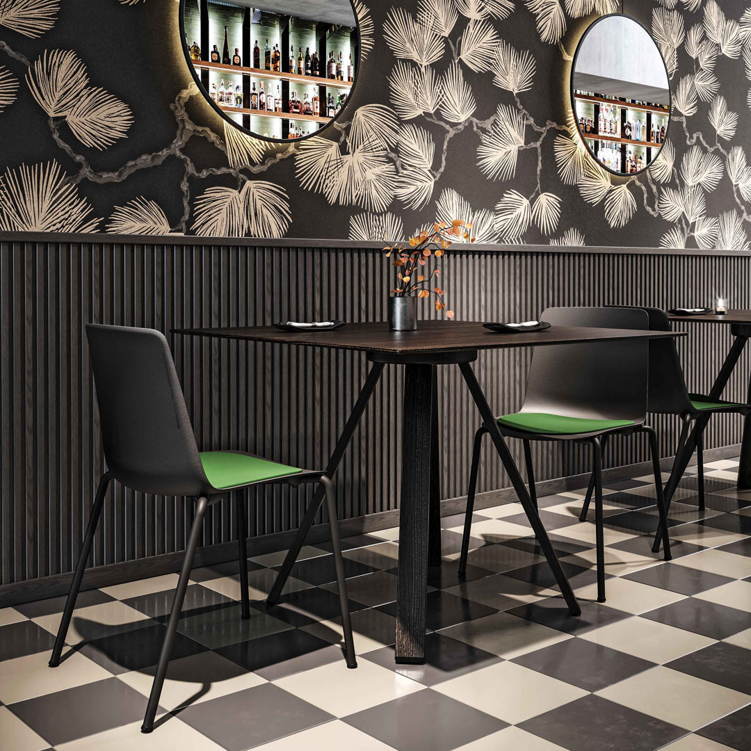 Black and green chairs with a geometric checkerboard floor and floral-patterned wallpaper. Stylish and modern dining setup.