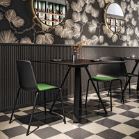 Black and green chairs with a geometric checkerboard floor and floral-patterned wallpaper. Stylish and modern dining setup.