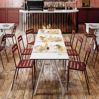 Red slatted chairs around a white table, set on a wooden floor in a stylish bar setting.