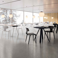 Modern dining space with white chairs, a black table, and neutral tones, highlighted by soft pendant lighting.