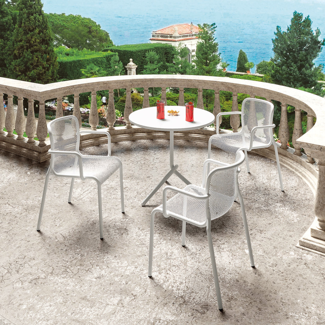 White outdoor chairs and table set against a scenic terrace backdrop, perfect for al fresco dining.