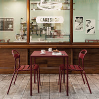 Red metal table with matching chairs, set against a wooden backdrop and pastel-colored shop interior.