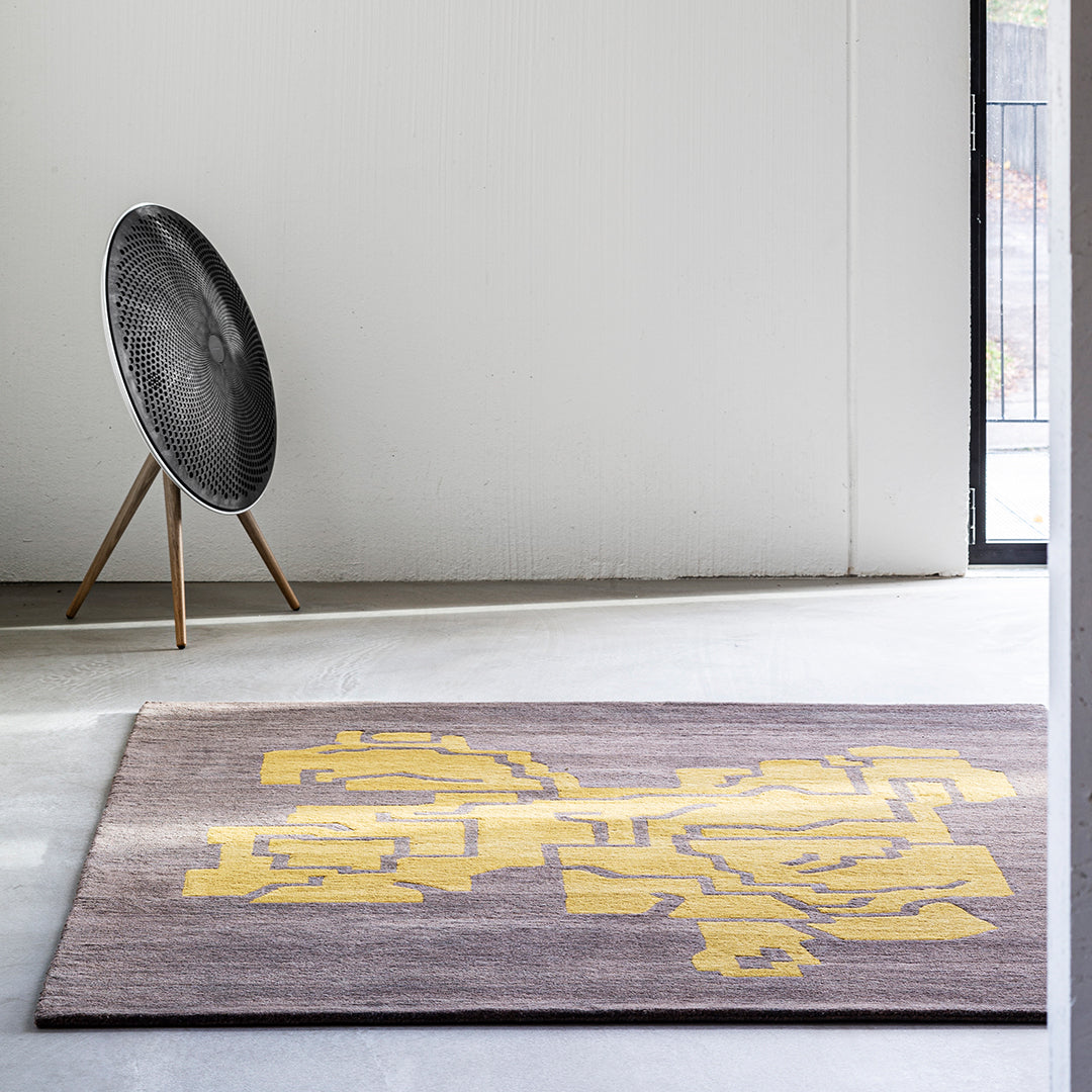 "Geometric patterned area rug featuring dark gray background and vibrant yellow accents."