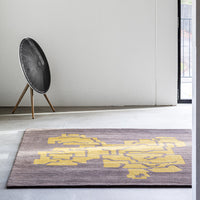 "Geometric patterned area rug featuring dark gray background and vibrant yellow accents."
