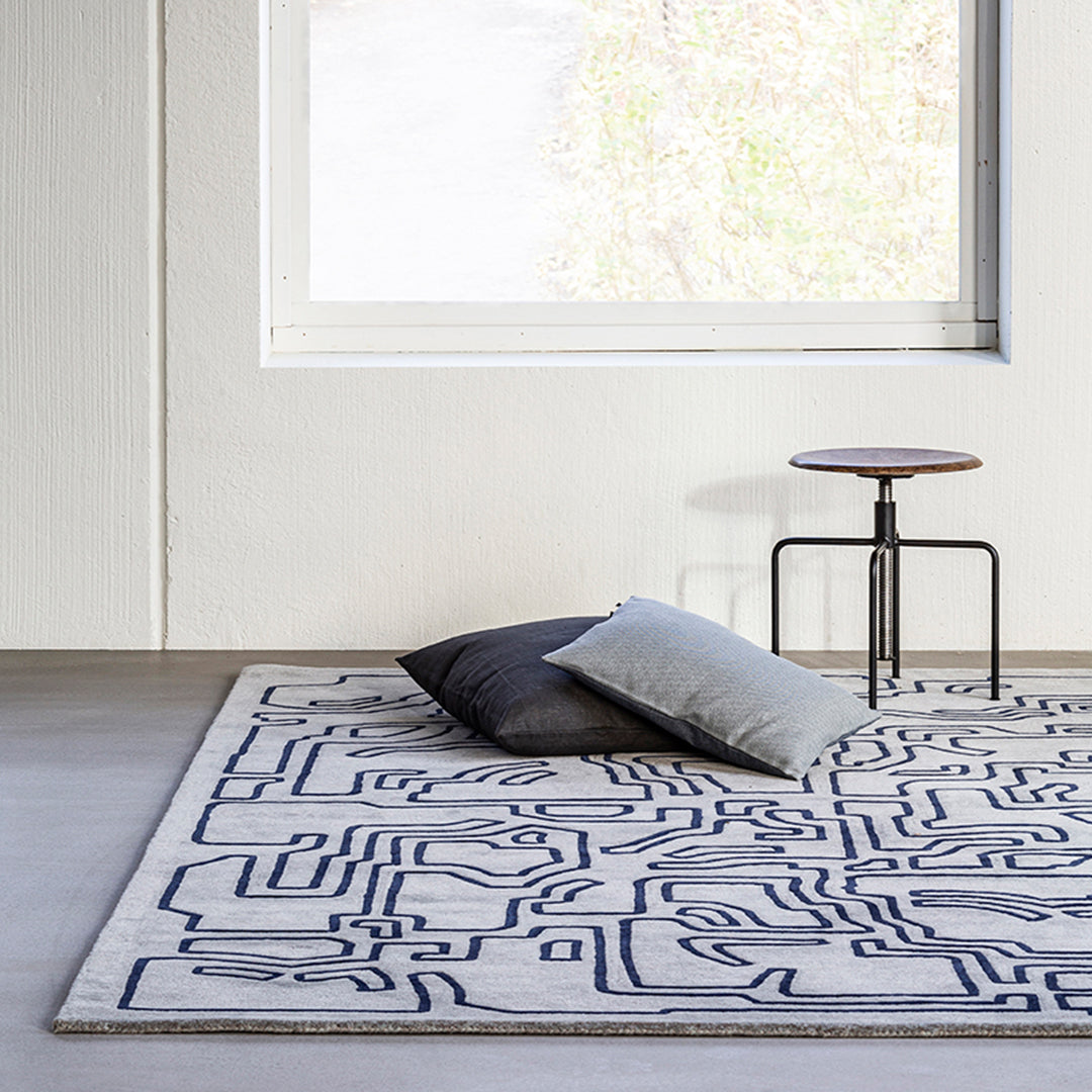 Abstract geometric rug in cream with navy blue lines; complements modern decor and softens living spaces.