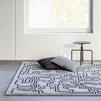 Abstract geometric rug in cream with navy blue lines; complements modern decor and softens living spaces.