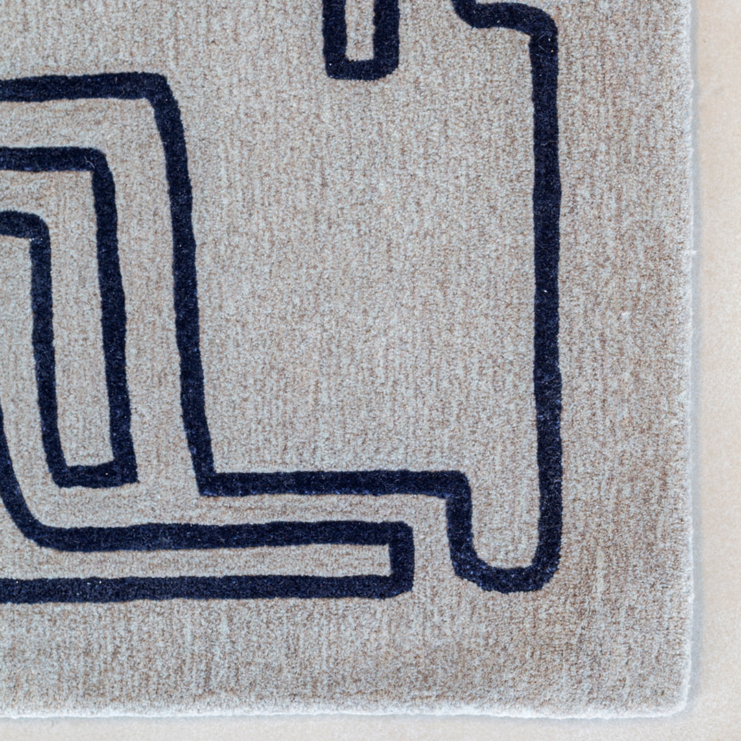 Gray rug with bold navy geometric pattern, featuring a maze-like design for a modern touch.