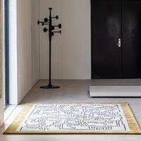 "Modern white rug with black geometric patterns and a golden border, perfect for contemporary interiors."