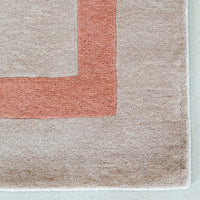 Soft beige rug featuring a contrasting orange and beige geometric pattern, perfect for modern interiors.