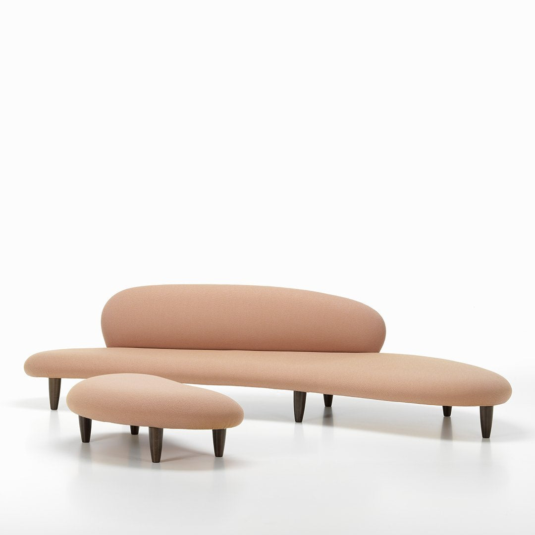 Curved sofa set in soft peach tones with smooth lines and a minimalist design, featuring tapered wooden legs.
