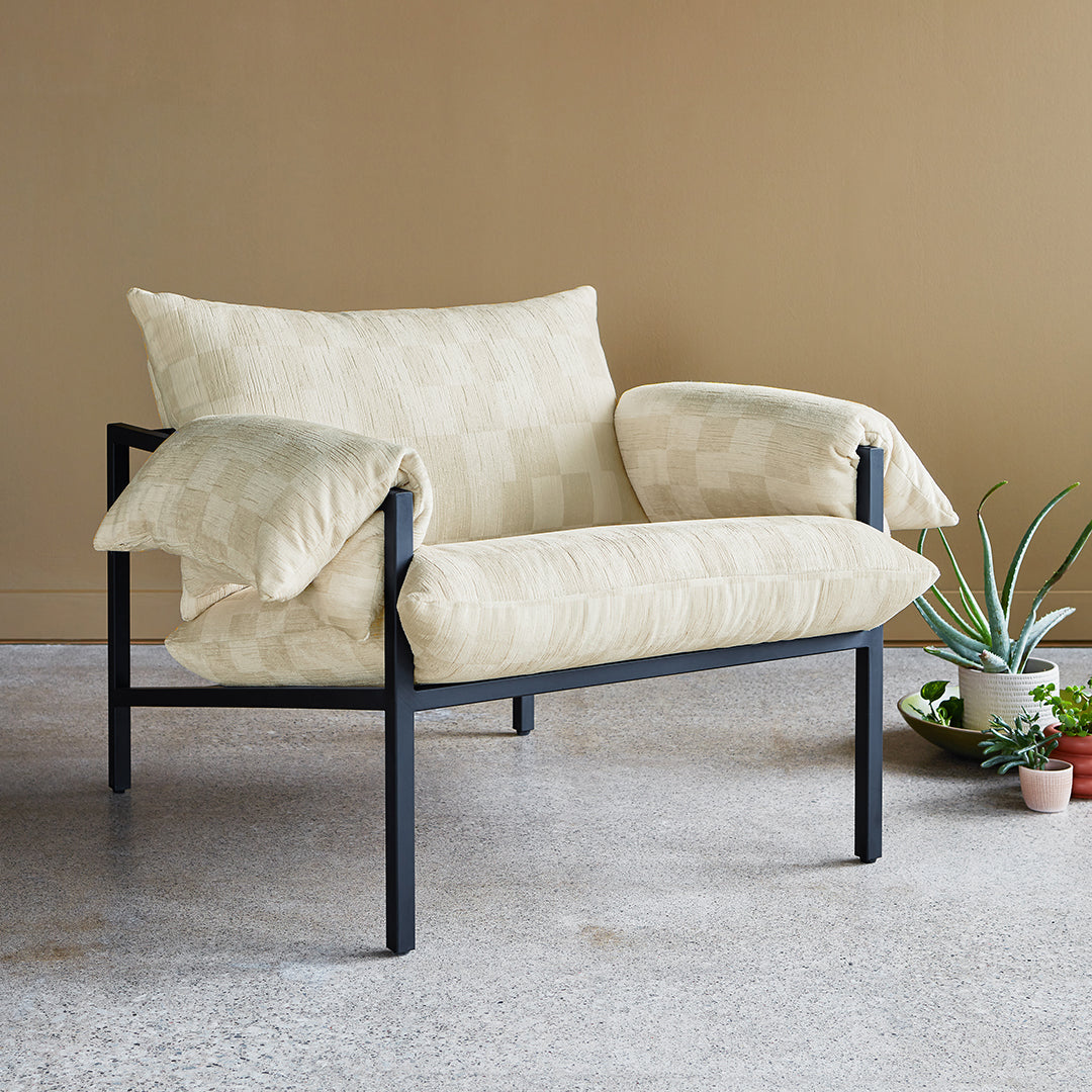 Light cream upholstered chair with geometric pattern, accented by a sleek black metal frame. Ideal for modern decor.