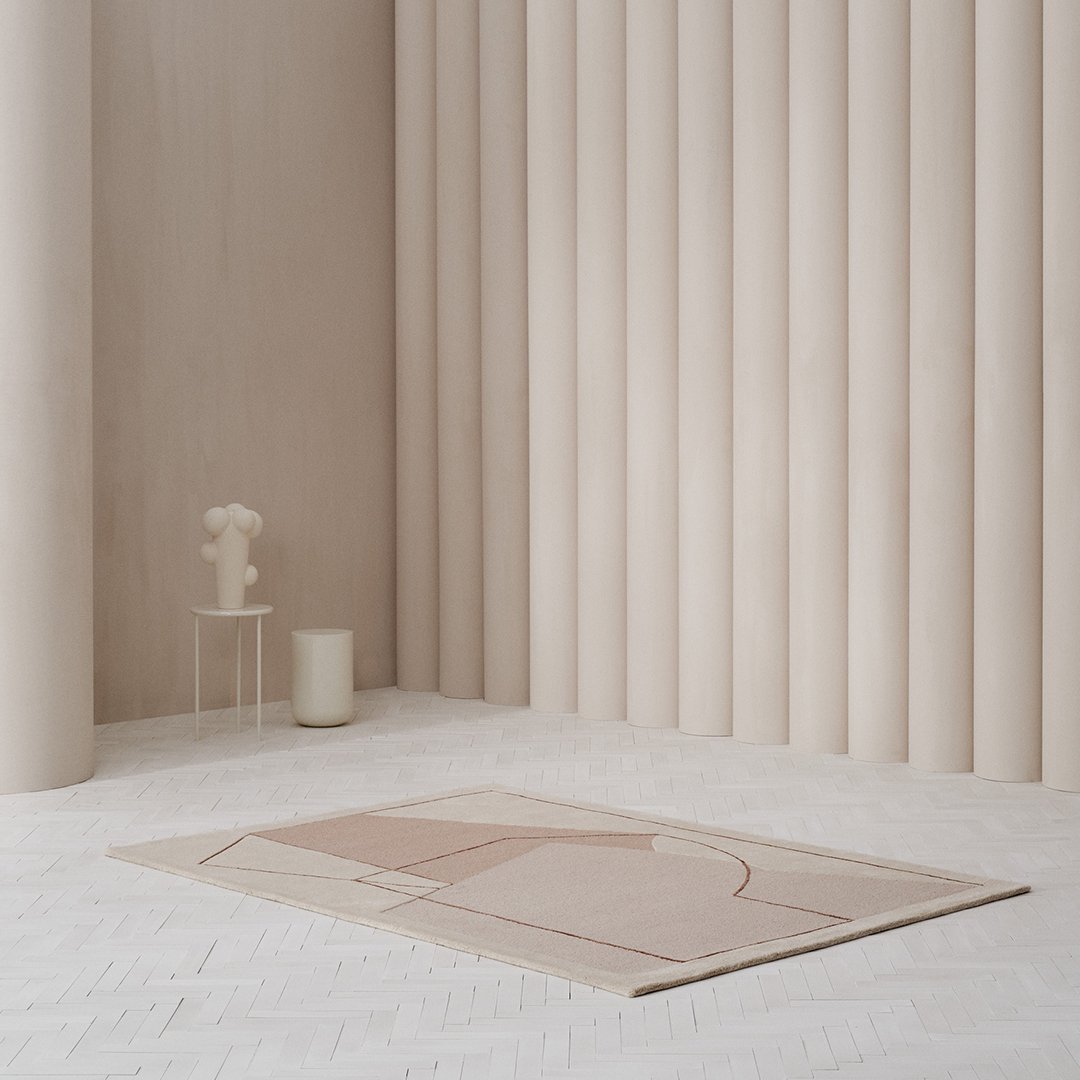 "Soft pink geometric patterned rug on a light-colored floor with neutral-toned walls and decor."
