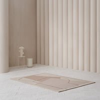 "Soft pink geometric patterned rug on a light-colored floor with neutral-toned walls and decor."