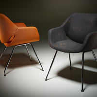 "Two modern chairs: one in orange, one in dark patterned gray, with sleek metal legs against a gradient background."