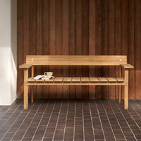 Natural wooden bench with a smooth finish, featuring slatted design and a warm color palette against a dark tiled floor.