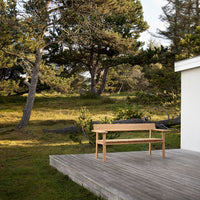 Light wooden bench featuring a natural finish, set against a serene outdoor backdrop of greens and soft earth tones.