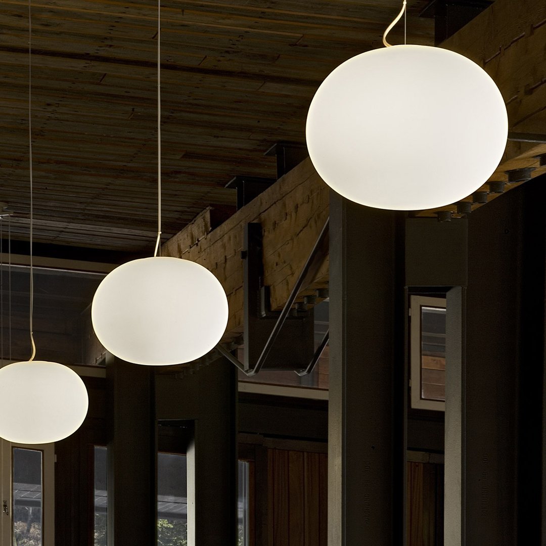Three smooth, round pendant lights in soft white glow, set against a wooden ceiling in a modern interior.