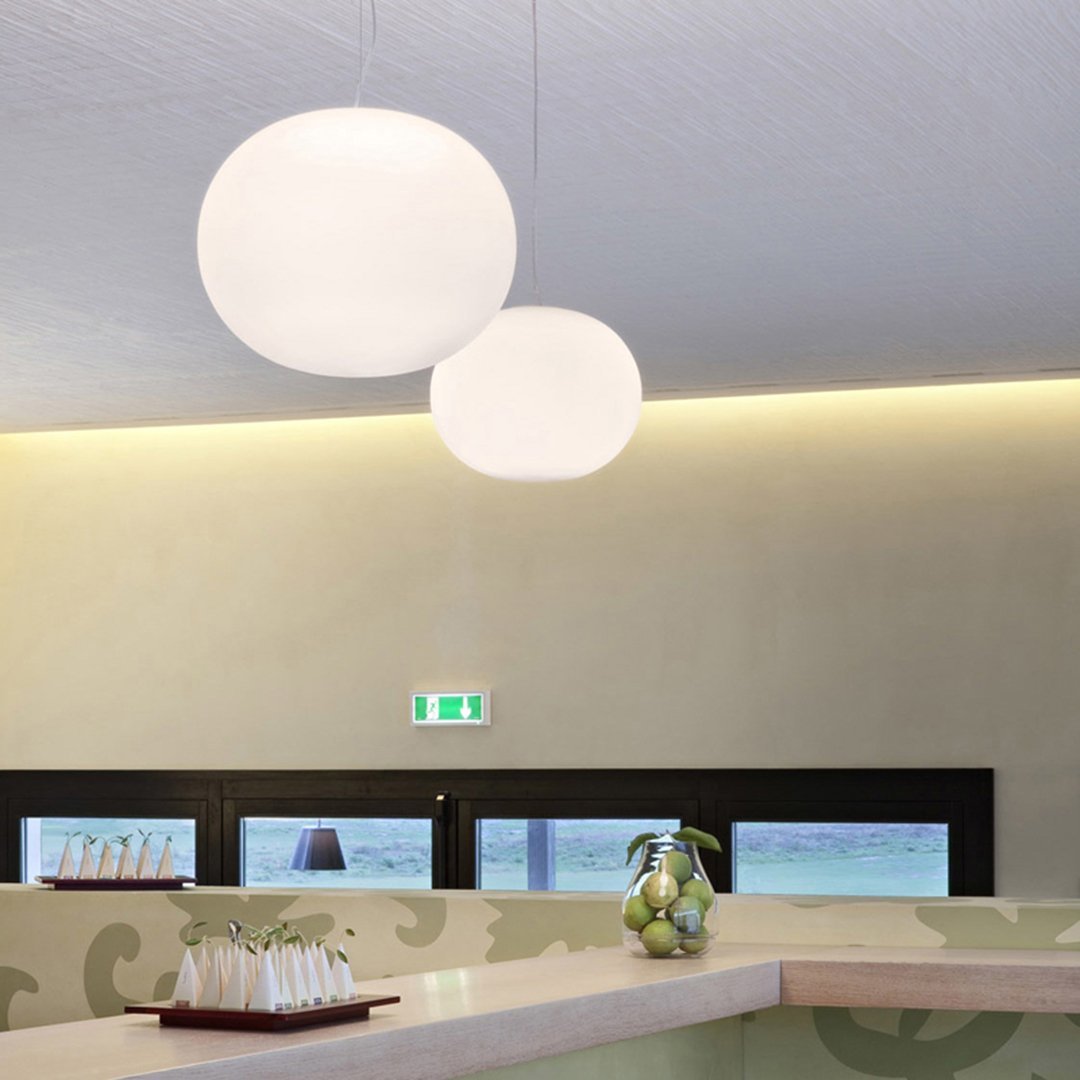 Two white globe pendant lights hanging in a modern space with a soft, neutral color palette and subtle patterns.