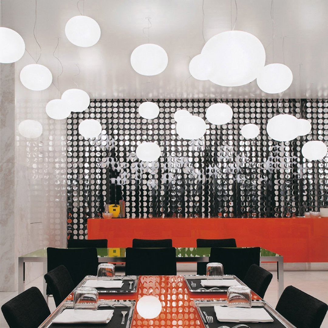 Modern dining space featuring black and white patterns, orange accents, and round white pendant lights.