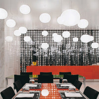 Modern dining space featuring black and white patterns, orange accents, and round white pendant lights.