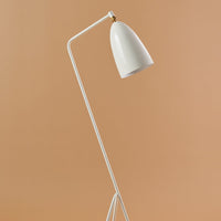 White floor lamp with a sleek, curved design against a warm beige background. Minimalist style with smooth finish.