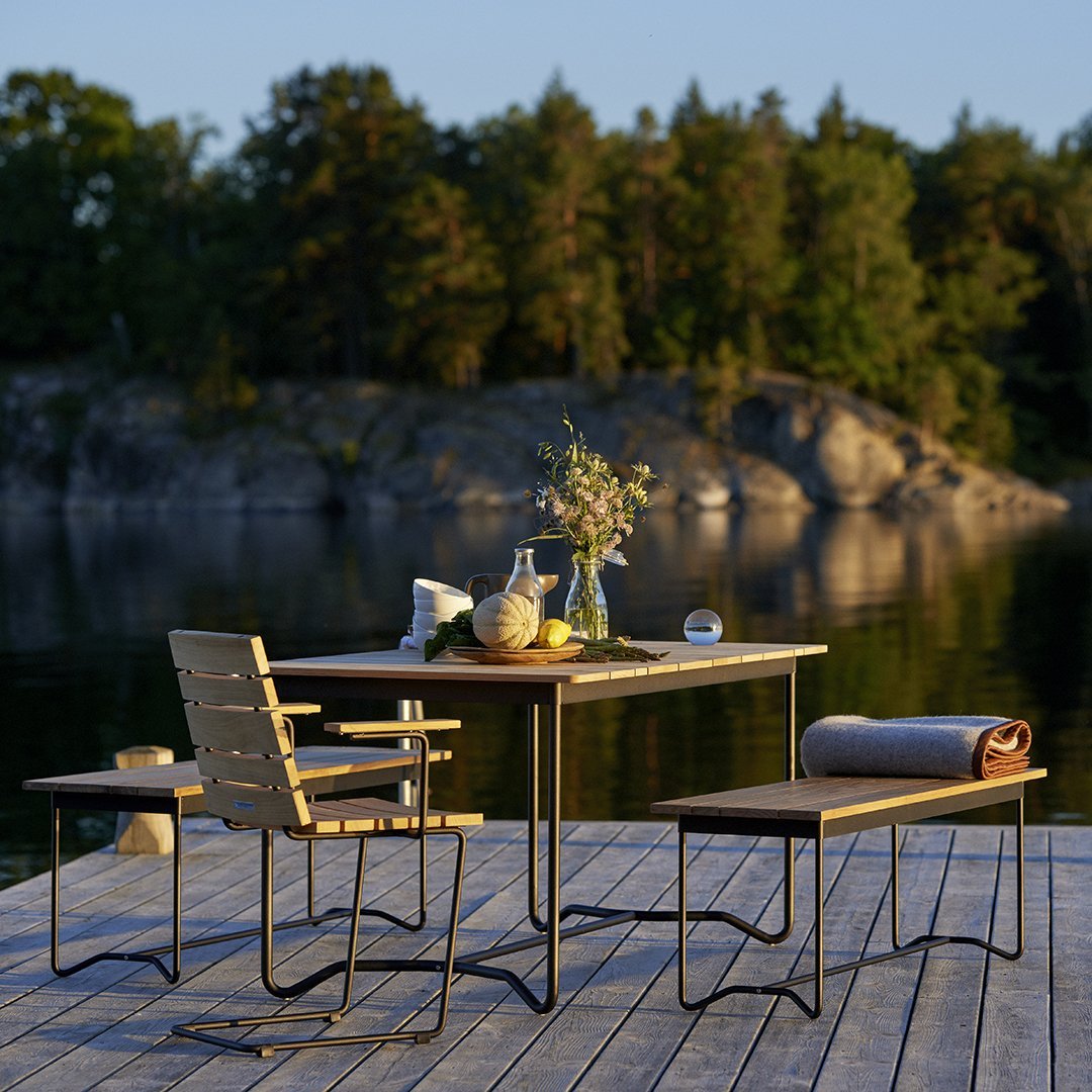 Modern wooden dining table with sleek black metal legs, accompanied by an elegant patterned table runner and natural greenery.