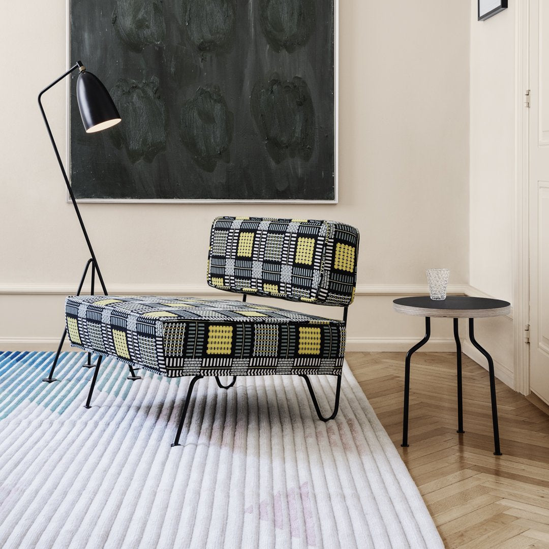 Stylish chair with a bold yellow and black geometric pattern on a gray background, paired with a sleek black side table.