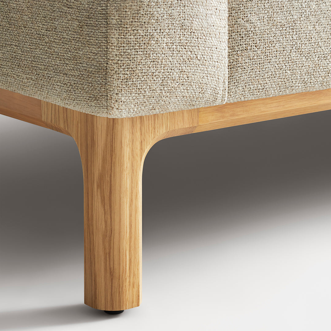 Light beige textured upholstery with natural oak wooden legs, showcasing a minimalist design and earthy tones.