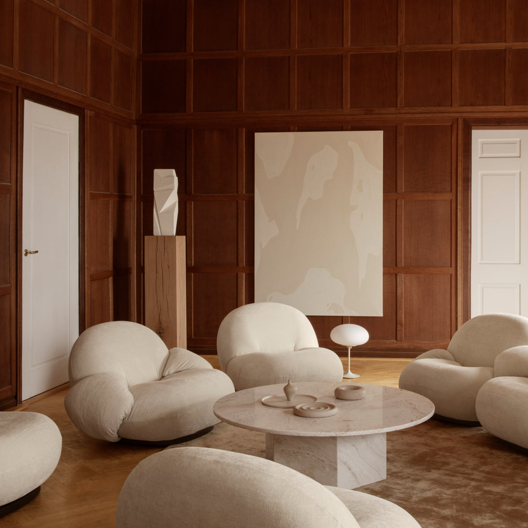 Soft beige and cream upholstery with light wood accents and abstract art in warm tones create a cozy modern living space.